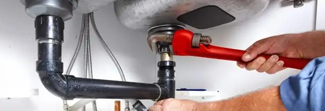 Garbage disposal repair technician tightening the sink drain and disposal connection in Allentown, PA