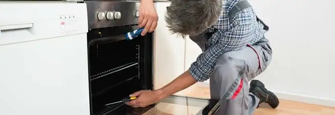 Oven repair technician inspecting and servicing an electric oven in Allentown, PA
