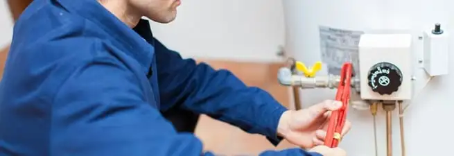Water heater repair technician adjusting the temperature control and gas valve in Allentown, PA